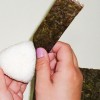 Bolinho de arroz passo 3: Retire o filme plástico e embrulhe o arroz com uma tira de nori (folha de alga japonesa).