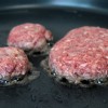 Passo 7: Aqueça o óleo numa frigideira em fogo médio e frite o hambúrguer por 1 minuto. Depois, vire com cuidado e tampe. Marque 5 minutos.