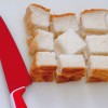 Passo 1: Corte o pão de forma em três partes na horizontal e depois em três partes na vertical. Coloque uma fatia de pão em cima da outra para facilitar