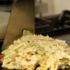 Com uma espátula, junte os ingredientes para que o okonomiyaki adquira a forma desejada. Tampe e aguarde até que se forme uma película sobre o repolho ou que a massa esteja firme para virar a preparação